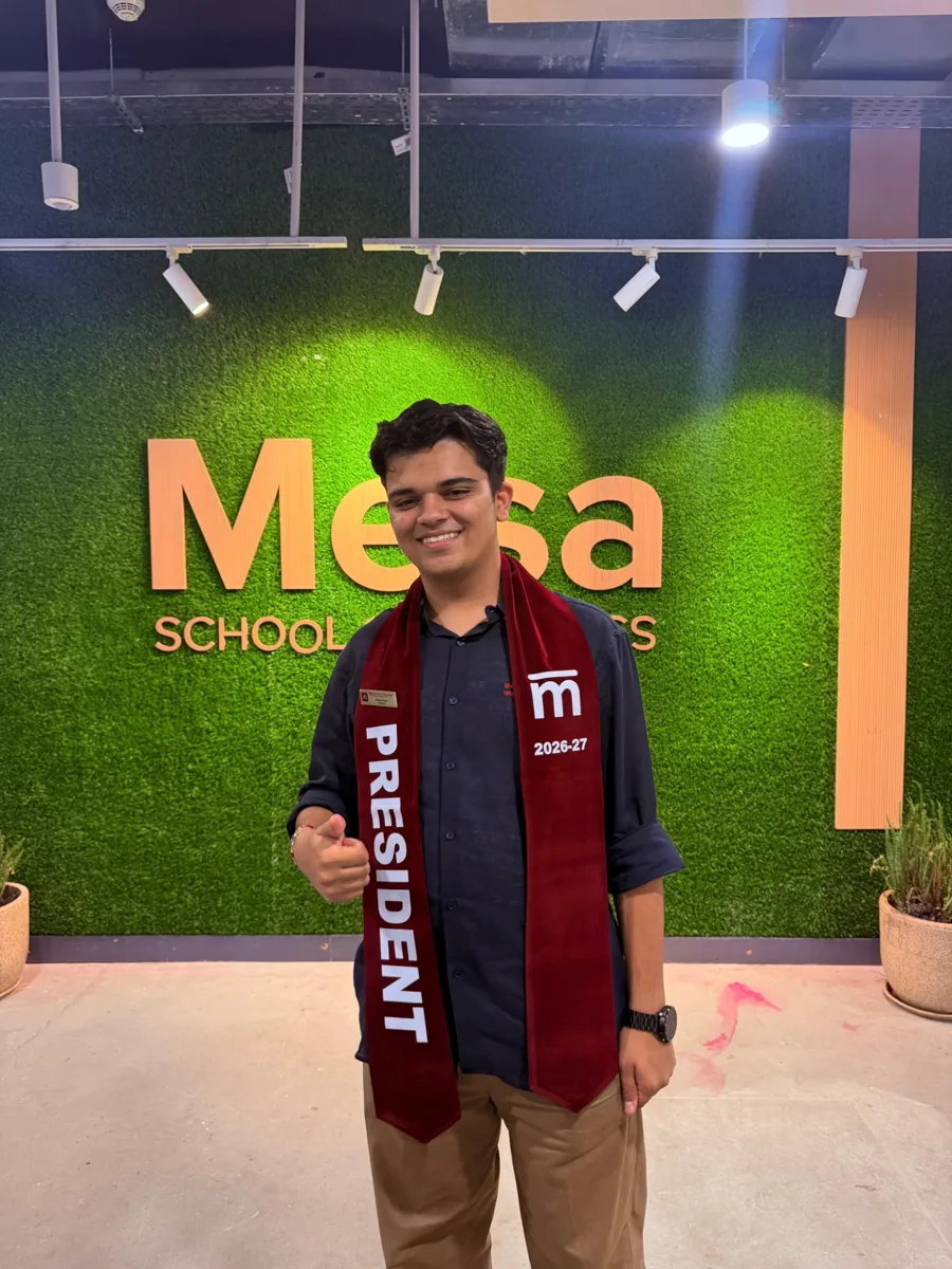 Shubh in a President 2026-27 sash in front of the Mesa School of Business sign